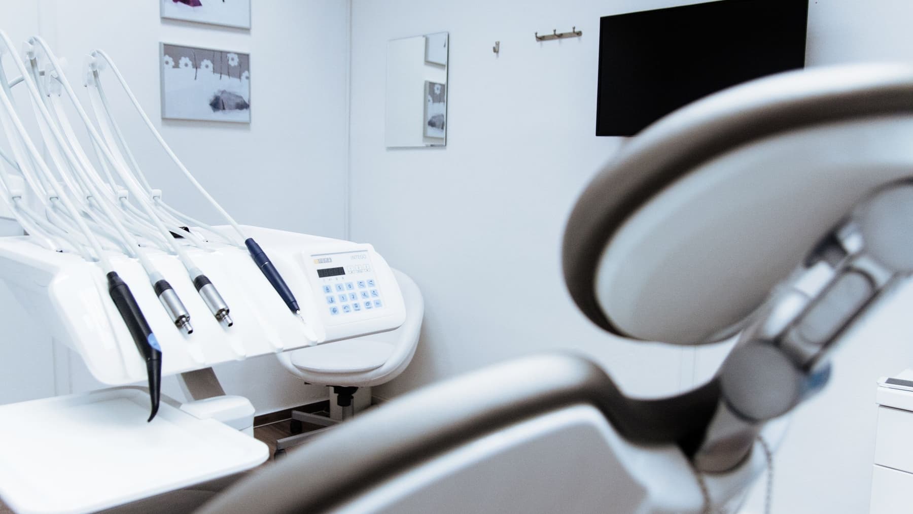 A treatment room at Evenbrook: a white dental chair, instrument tray and wall-mounted screen in daylight.