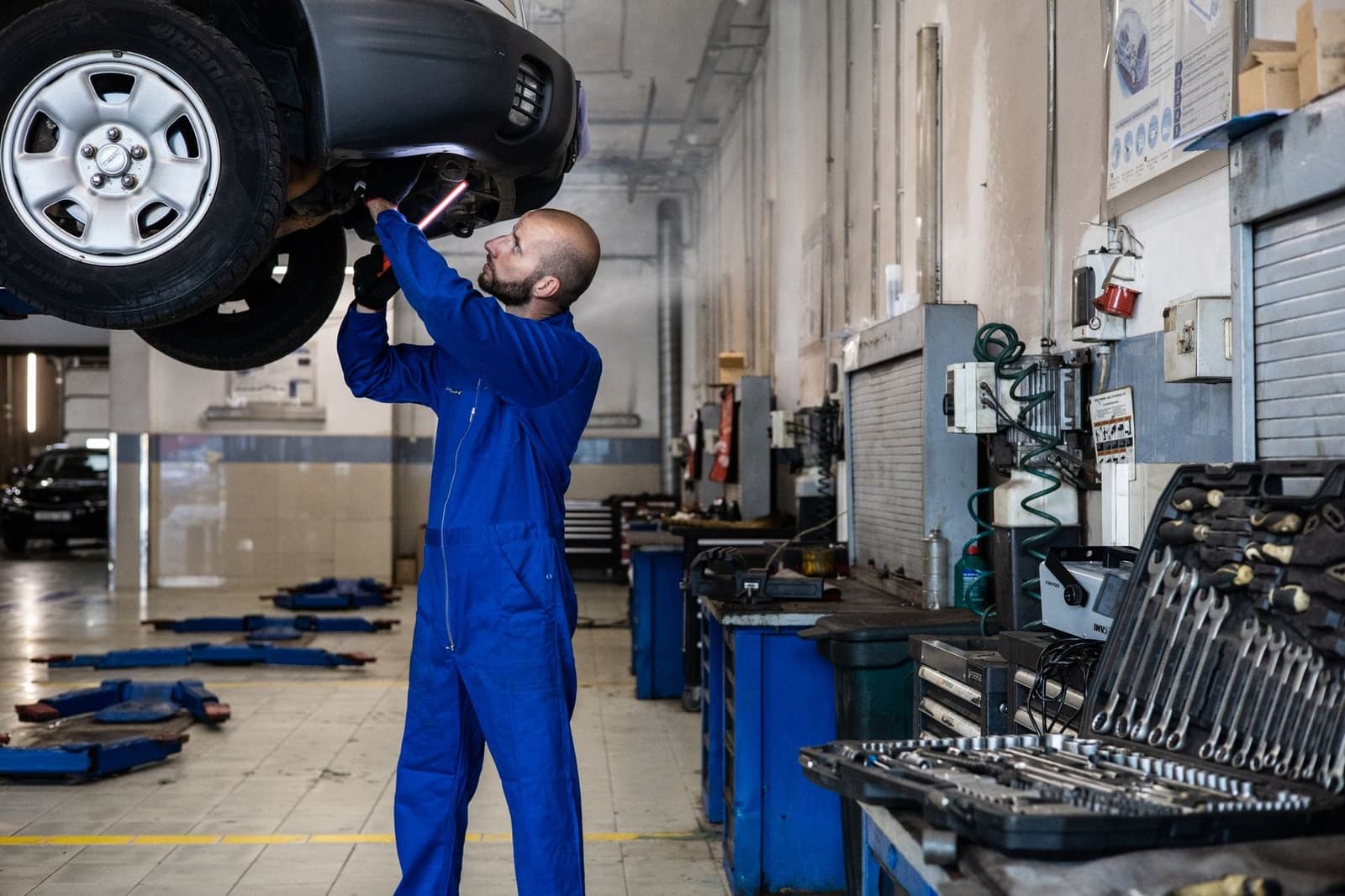 A mechanic inspecting a car raised on a lift.